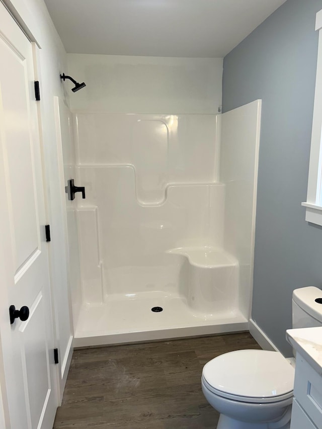 bathroom featuring vanity, toilet, wood finished floors, and a shower