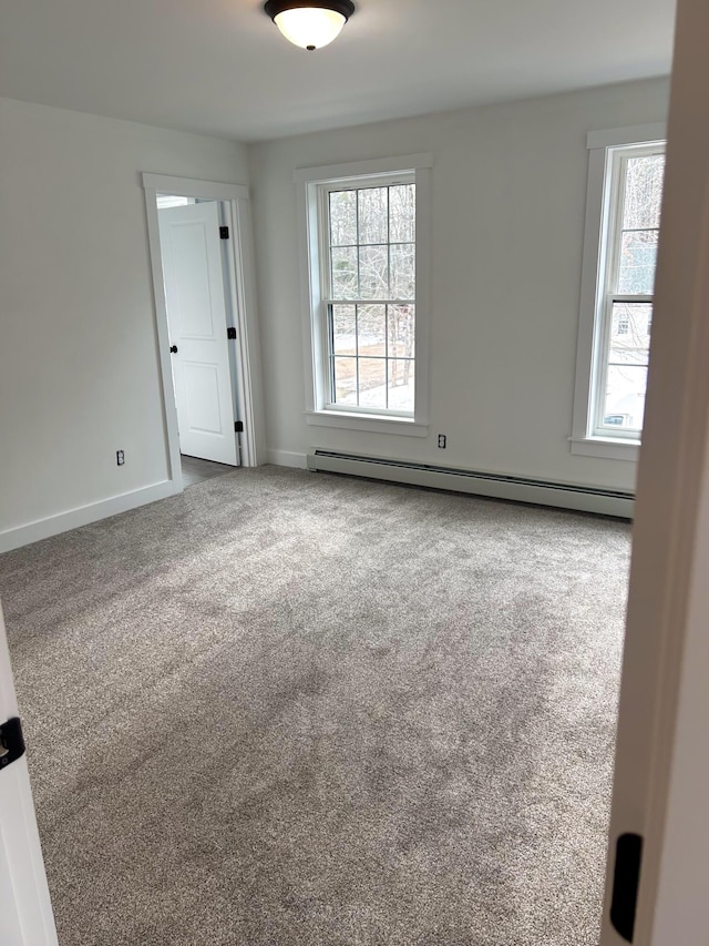 empty room with a baseboard radiator, baseboards, and carpet