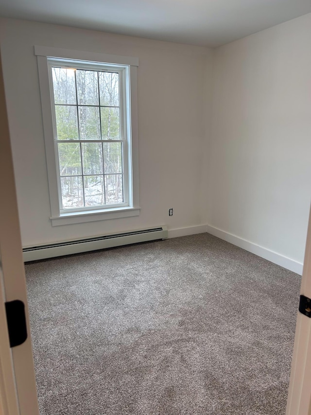 carpeted empty room with a baseboard heating unit and baseboards