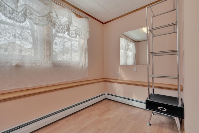 unfurnished dining area with baseboard heating, crown molding, and wood finished floors