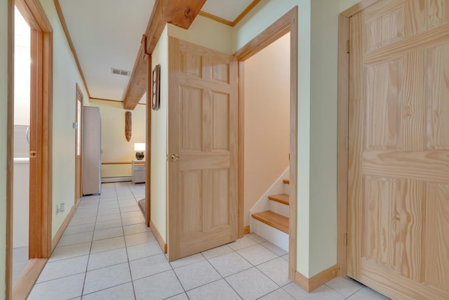 hallway featuring visible vents, crown molding, baseboards, stairway, and light tile patterned flooring