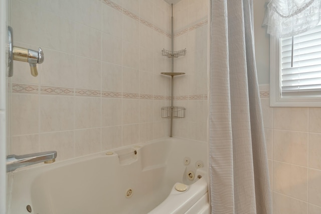 bathroom with tile walls and a combined bath / shower with jetted tub