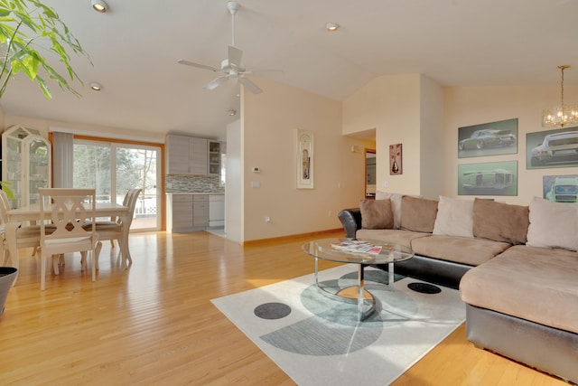 living area with baseboards, high vaulted ceiling, light wood-style flooring, and ceiling fan with notable chandelier