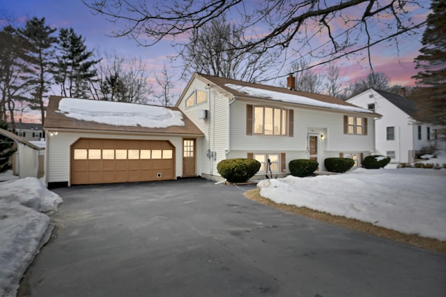 bi-level home featuring driveway, a chimney, and an attached garage