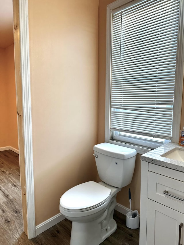 half bathroom with toilet, baseboards, and wood finished floors