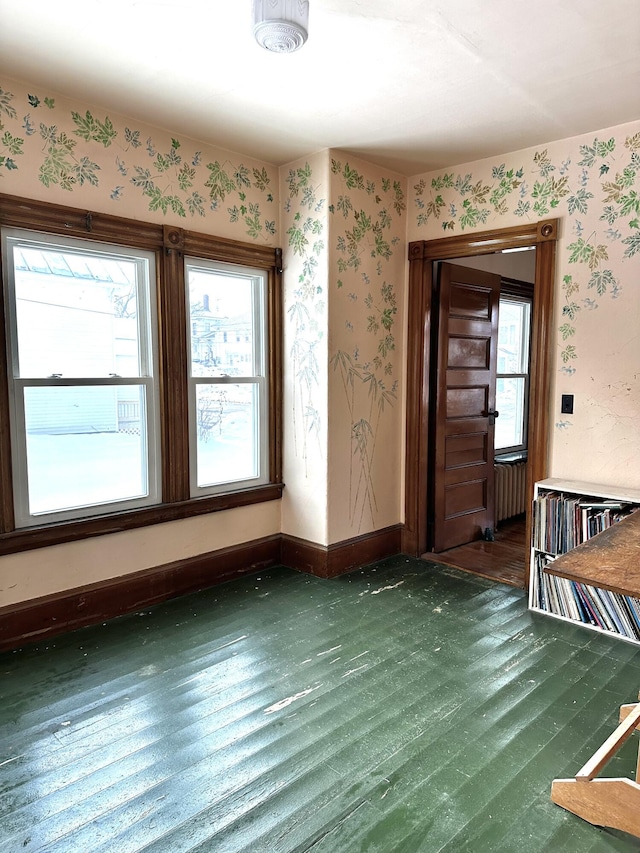 spare room featuring wallpapered walls, wood finished floors, and baseboards