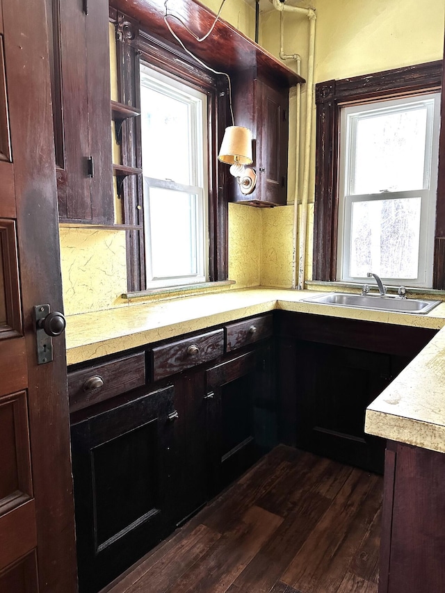 kitchen with a sink, plenty of natural light, dark wood finished floors, and light countertops