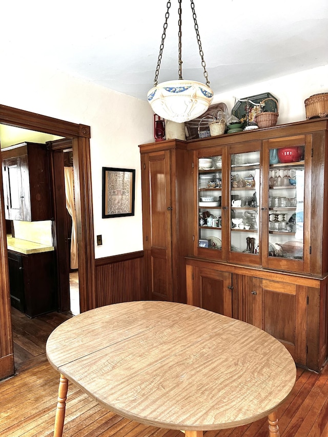 dining area featuring a wainscoted wall, wooden walls, and hardwood / wood-style flooring