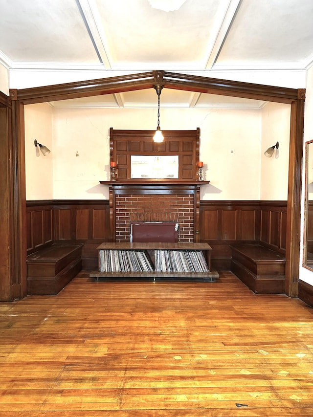 living area with a brick fireplace, wood finished floors, and wainscoting