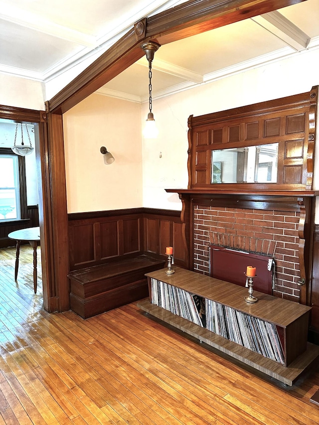 living room with a wainscoted wall, light wood finished floors, coffered ceiling, beam ceiling, and crown molding