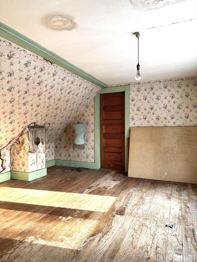 additional living space featuring lofted ceiling, hardwood / wood-style floors, and wallpapered walls