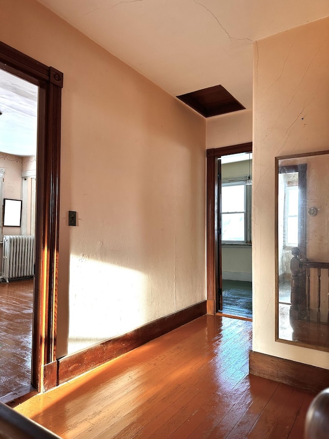 empty room with baseboards, wood-type flooring, and radiator