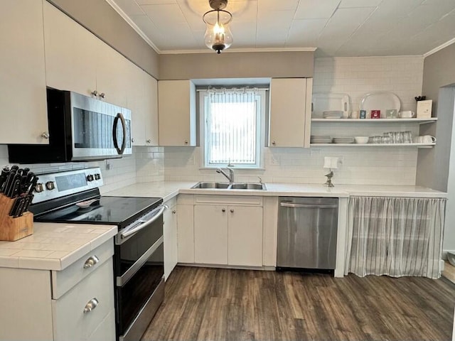 kitchen featuring dark wood-style floors, stainless steel appliances, crown molding, and a sink