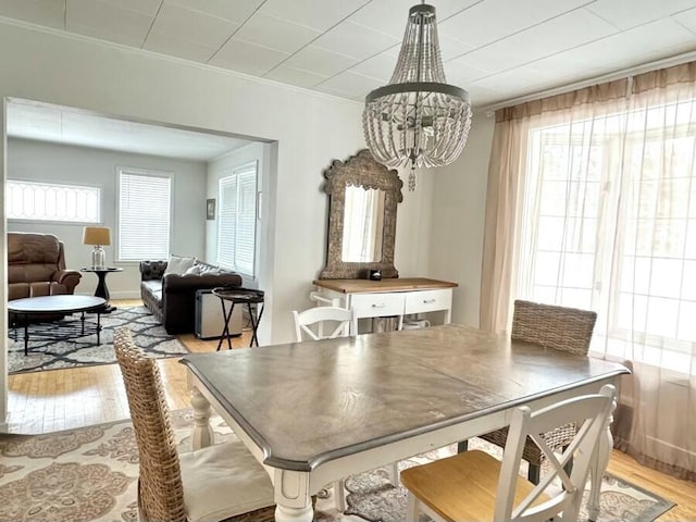 dining area featuring light wood-style flooring, ornamental molding, and a chandelier