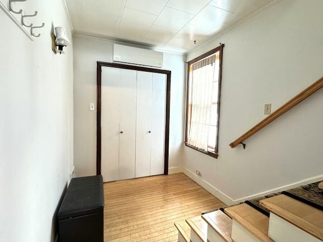 interior space with a wall unit AC, crown molding, and wood-type flooring