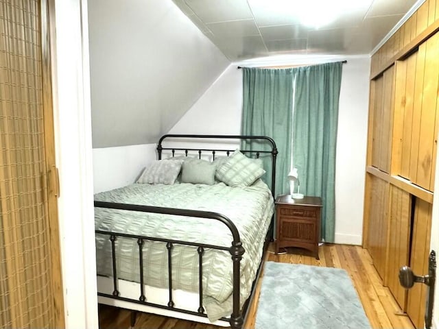 bedroom with light wood-style flooring and vaulted ceiling