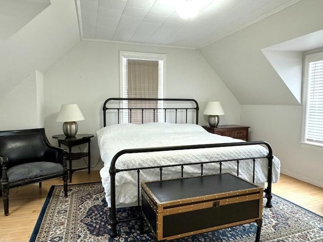 bedroom featuring ornamental molding, lofted ceiling, and wood finished floors