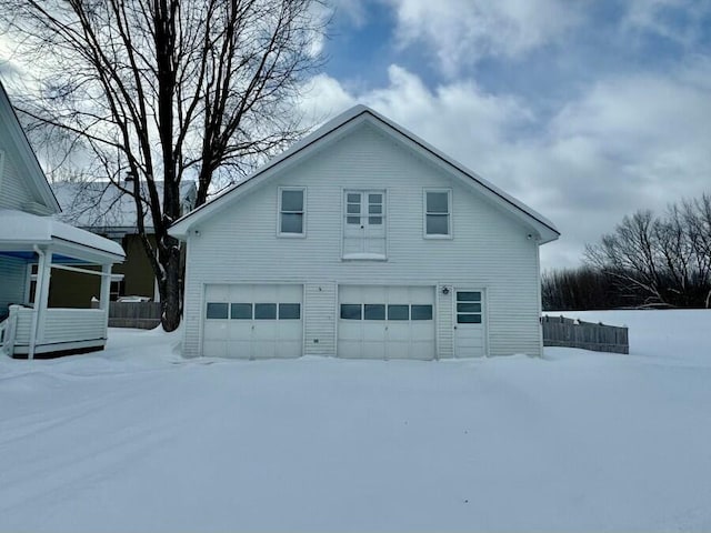 snow covered property featuring an attached garage