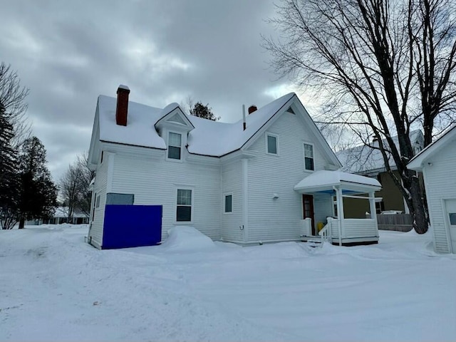 snow covered property with a chimney