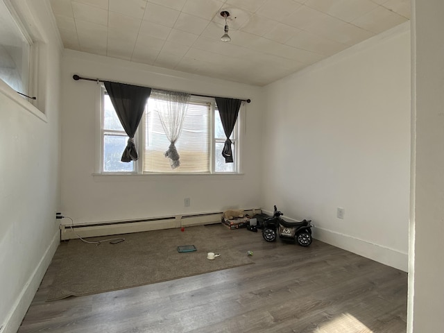 spare room with baseboards, baseboard heating, and wood finished floors