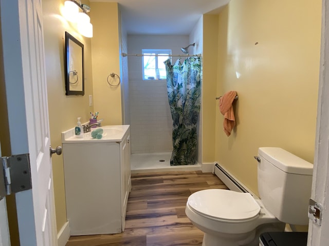 bathroom with a stall shower, toilet, a baseboard radiator, wood finished floors, and vanity