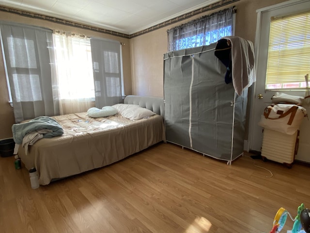 bedroom with ornamental molding and wood finished floors