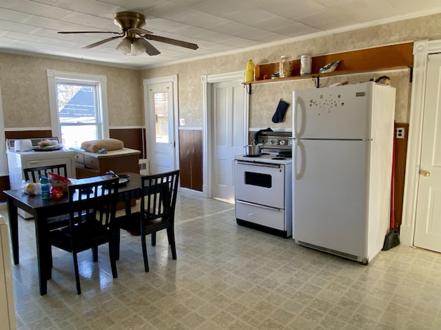 kitchen with white appliances, wallpapered walls, wainscoting, crown molding, and light floors