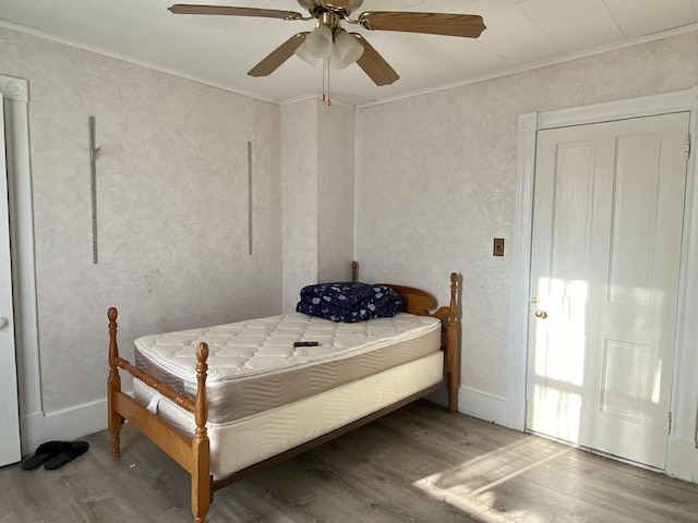 bedroom featuring crown molding, a ceiling fan, and wood finished floors