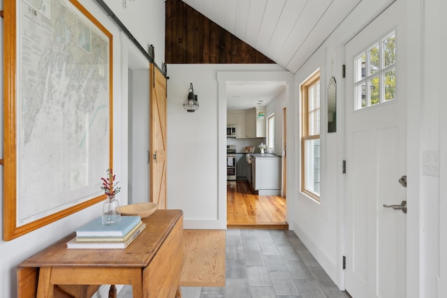 463 Back Meadow Rd, Damariscotta, ME 04543 - foyer featuring lofted ceiling, a barn door, baseboards, and wood finished floors