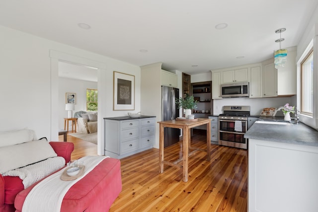 463 Back Meadow Rd, Damariscotta, ME 04543 - kitchen featuring appliances with stainless steel finishes, a sink, light wood finished floors, dark countertops, and hanging light fixtures