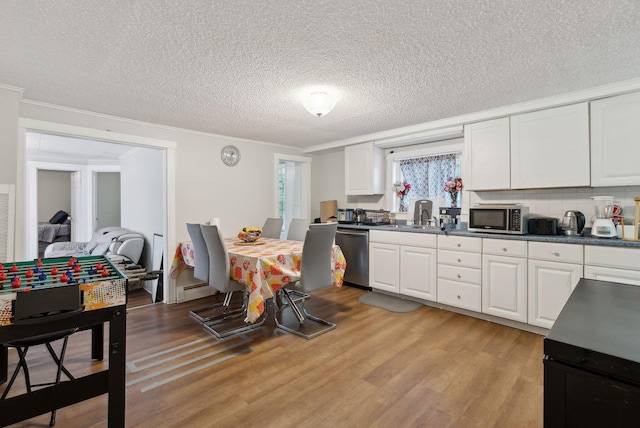 kitchen with appliances with stainless steel finishes, white cabinetry, light wood-type flooring, and crown molding