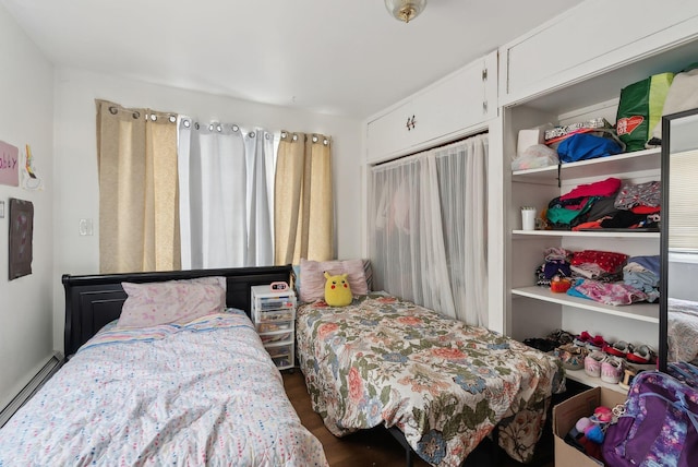 bedroom with baseboard heating and wood finished floors