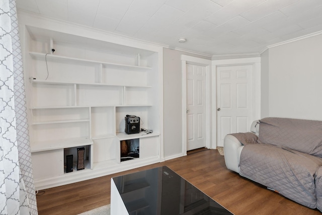 living area with baseboards, built in shelves, wood finished floors, and ornamental molding