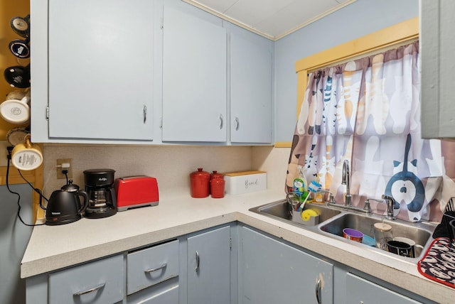 kitchen featuring light countertops, gray cabinets, and a sink