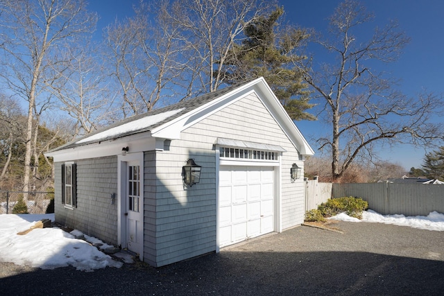 detached garage featuring driveway and fence