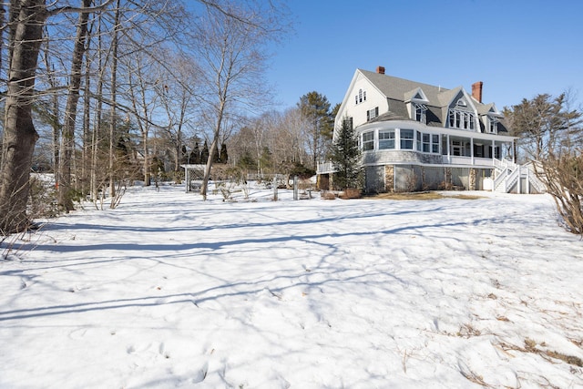 snow covered property with stairs and a chimney