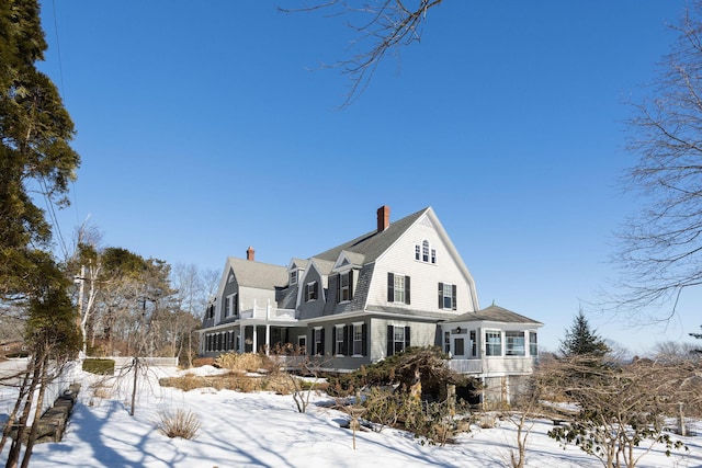 exterior space with a sunroom, a chimney, and a gambrel roof