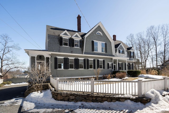 view of front of house featuring a fenced front yard, a chimney, and a gambrel roof