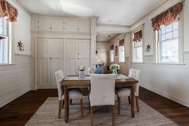 dining space featuring dark wood-style floors, ornamental molding, and wainscoting