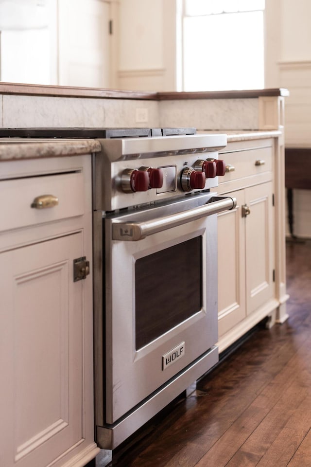 room details featuring dark wood-style floors, premium stove, white cabinetry, and light countertops