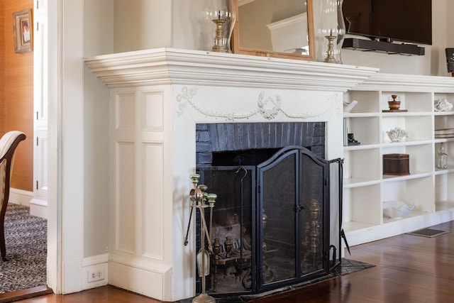 details featuring a brick fireplace and wood finished floors