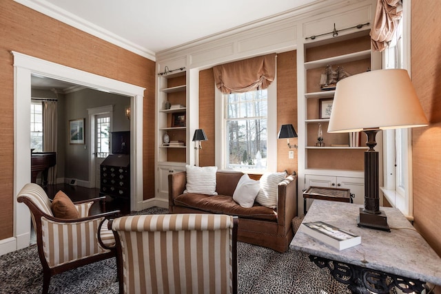 sitting room with ornamental molding, built in shelves, and baseboards