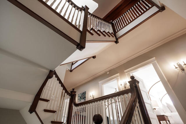 stairs with a towering ceiling and crown molding