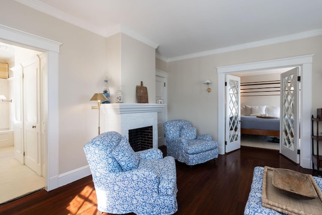 sitting room with crown molding, a fireplace, baseboards, and wood finished floors