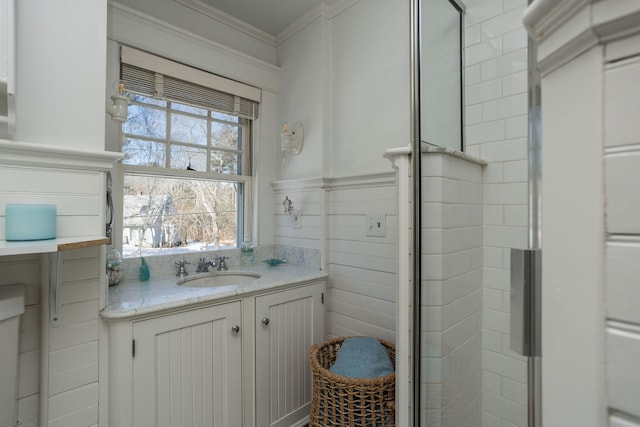 full bathroom with wainscoting, crown molding, a shower stall, and vanity