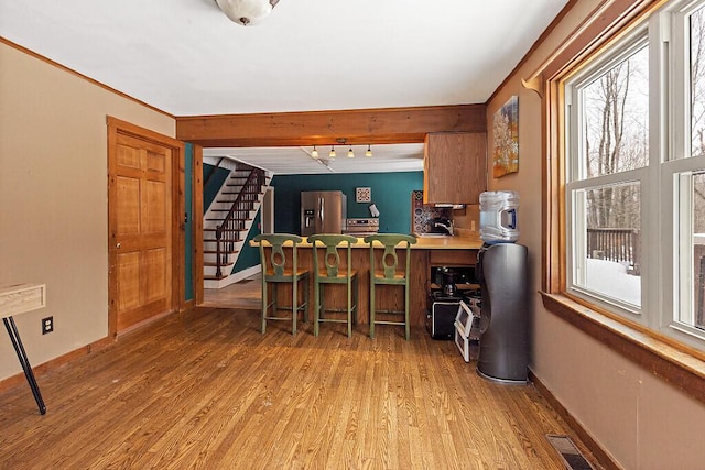 interior space featuring stainless steel fridge with ice dispenser, visible vents, light wood-style floors, baseboards, and stairs