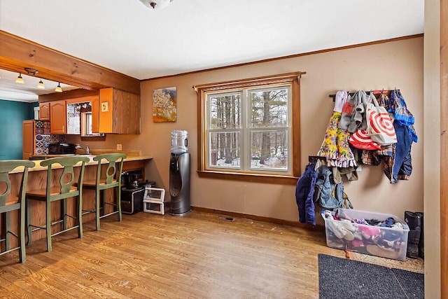 kitchen featuring a breakfast bar area, baseboards, fridge, light wood-type flooring, and brown cabinets