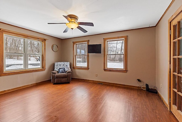 unfurnished room with ceiling fan, baseboards, wood finished floors, and ornamental molding