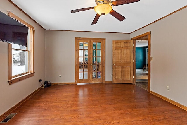 empty room with plenty of natural light, visible vents, wood finished floors, and french doors