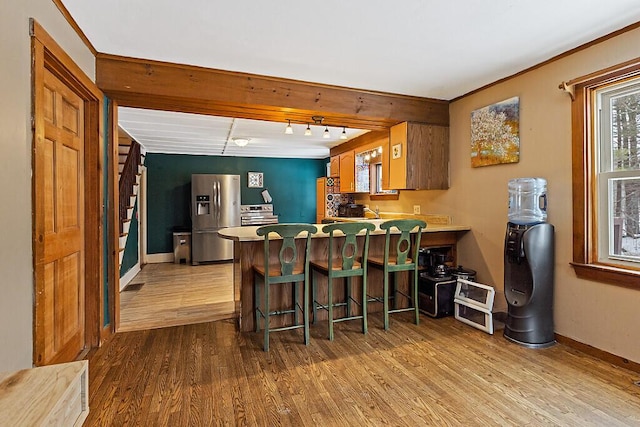 kitchen with a peninsula, wood finished floors, stainless steel fridge, and baseboards